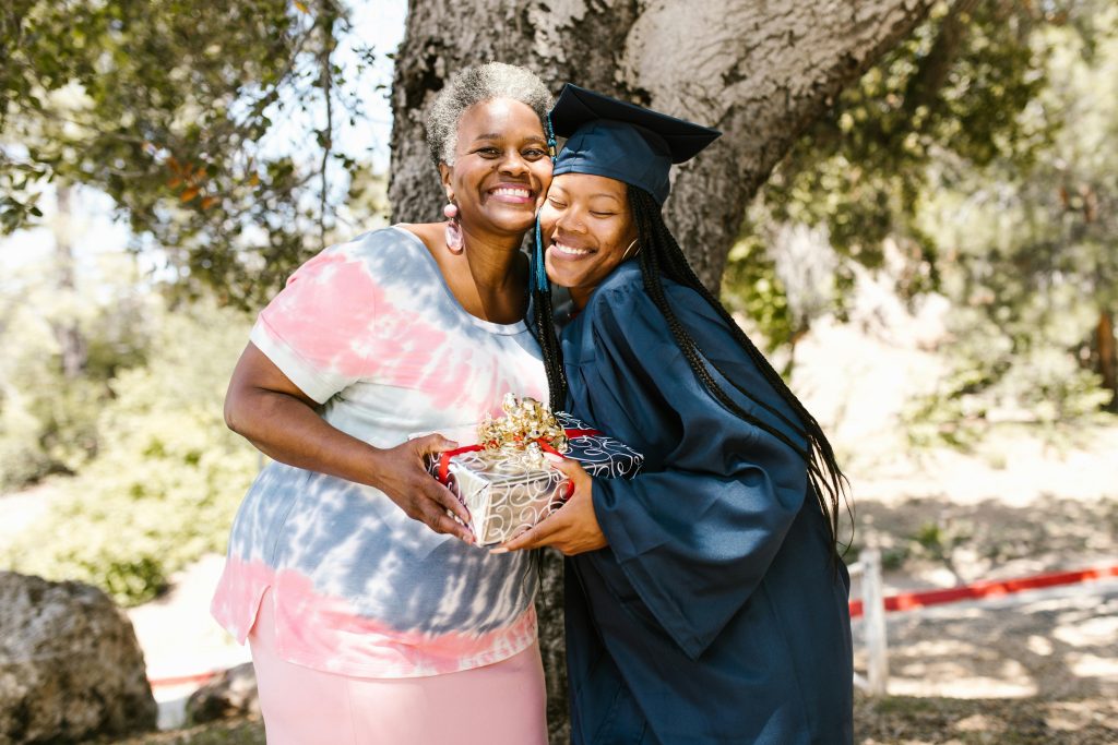 Elder and younger person huging, graduation cap